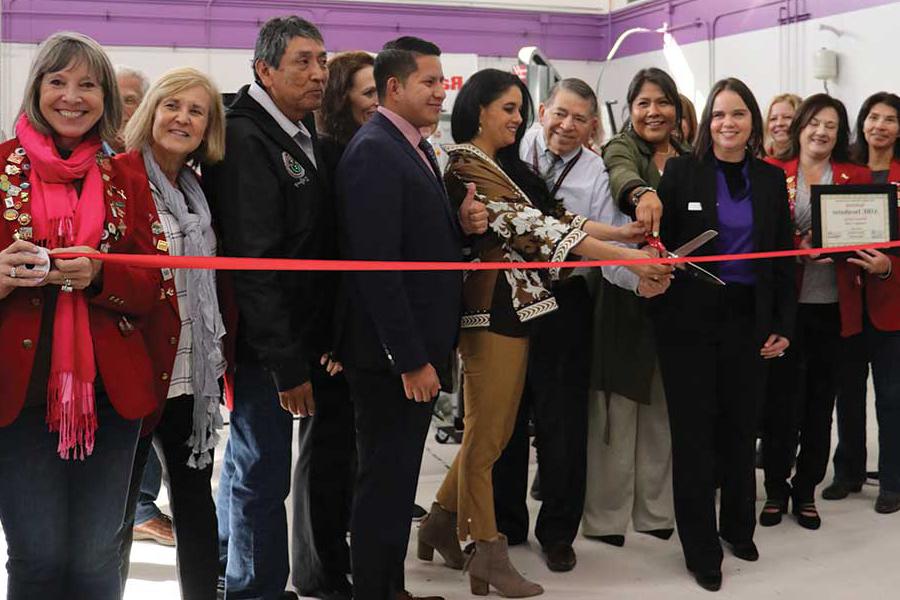 Individuals standing in front of a ribbon cutting