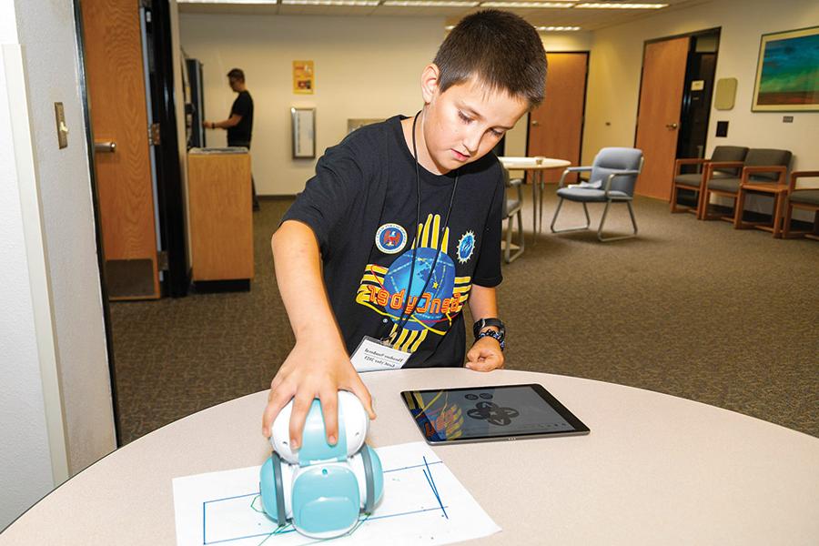 Young GenCyber student works with mini robot the Artie 3000 while attending the science camp.