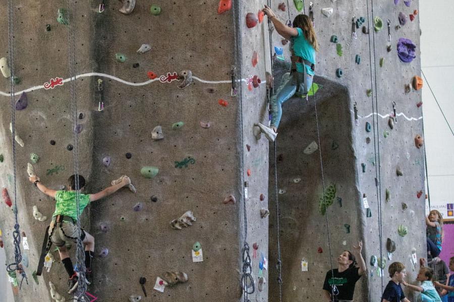 Three Kids Kollege students climbing on the 室内攀岩 wall at HHPC