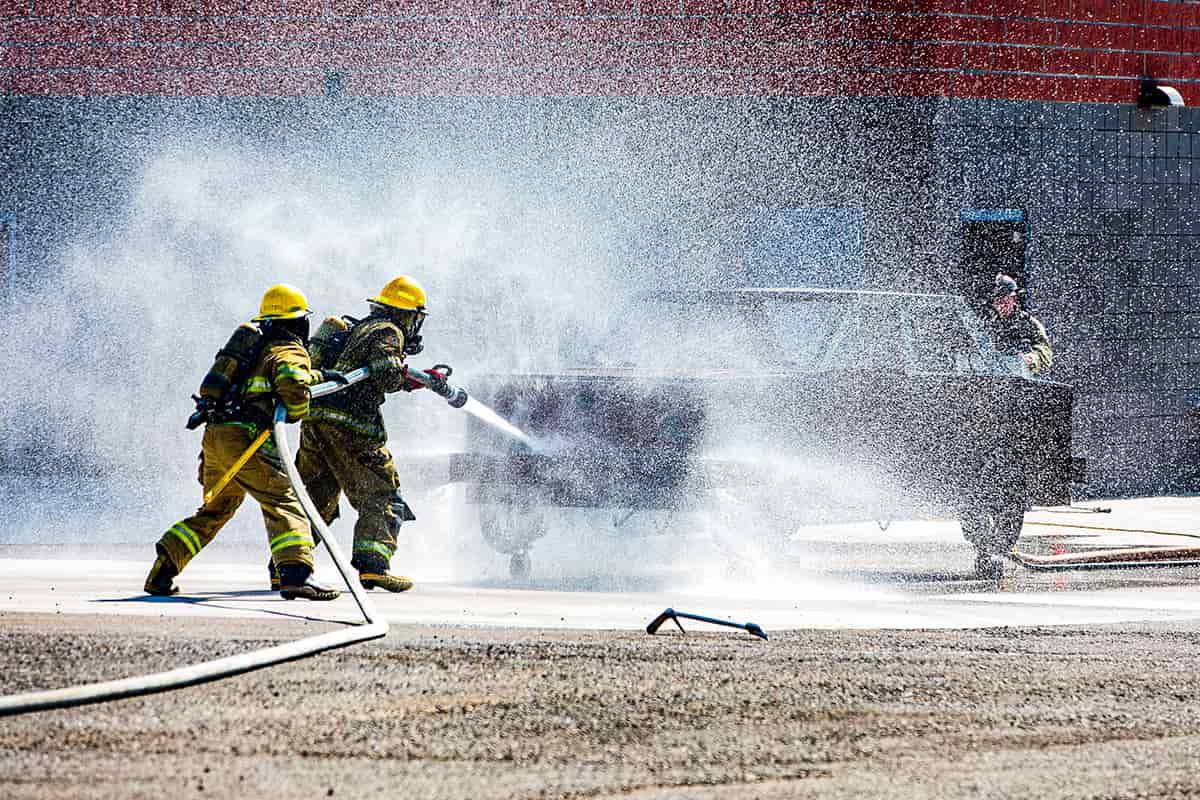 两名消防员在消防科学练习塔练习扑灭车辆火灾.