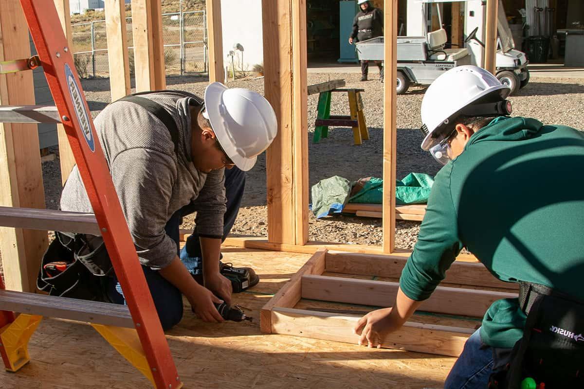 Two San Juan College students working on framing a building