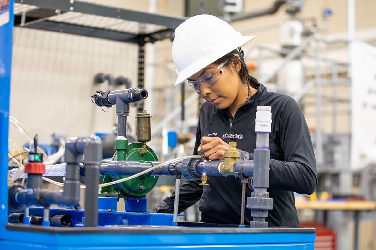 An individual in a hard hat inspects valves and equipment