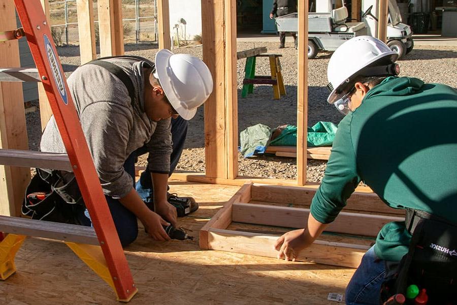 Two San Juan College students working on framing a building